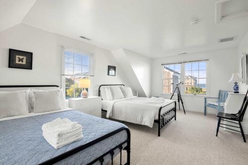 a white bedroom with two beds and a chair at Stunning Home with Water Views in Sandwich