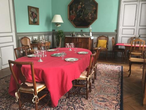a dining room with a red table and chairs at Le Fassardy in Châteauroux