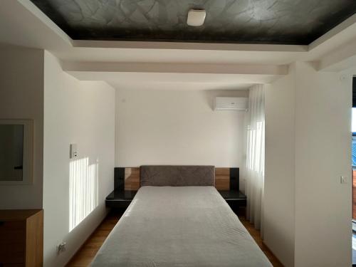 a bed in a room with white walls and a ceiling at Centar Crnjanski 1 in Jagodina