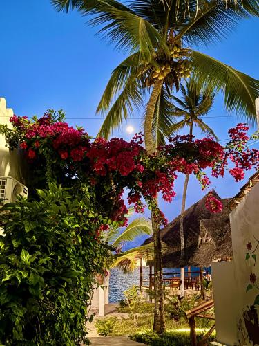 a palm tree with pink flowers on a fence at AVO Boutique Hotel in Dikoni