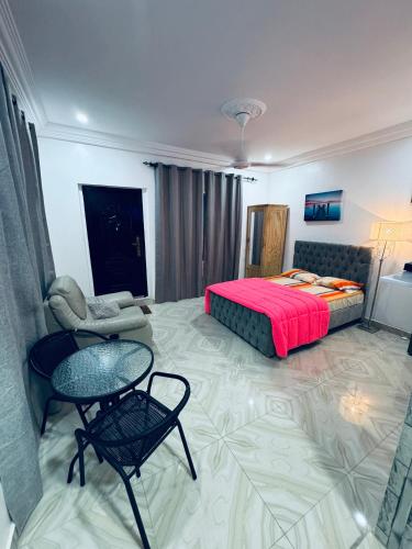 une chambre avec un lit, une table et des chaises dans l'établissement Jawara Kunda Apartments, à Tujering