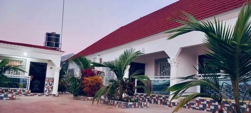 - un bâtiment blanc avec des palmiers dans la cour dans l'établissement Jawara Kunda Apartments, à Tujering