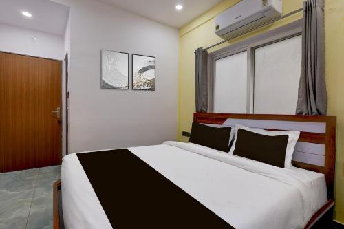 a bedroom with a white and black bed and a window at Collection O Lorven Grand in Visakhapatnam