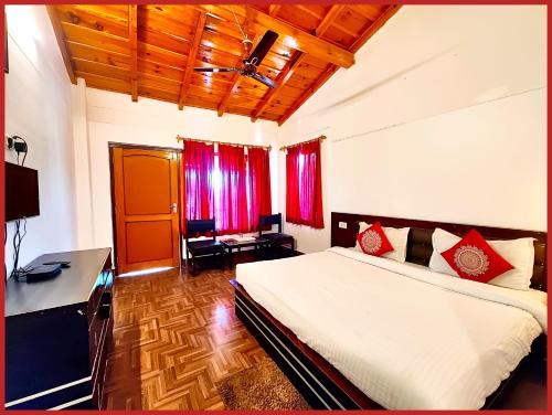 a bedroom with a bed and a desk and red curtains at Hotel Sapphire Stay- A Luxury Resort with All Room Attached Balcony and Valley View - Wifi - Restaurant - Parking and Children Play Ground Available - Best Resort in Nainital in Nainital