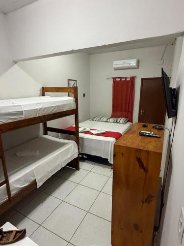 a small room with two bunk beds and a desk at Pousada Praiana Jericoacora in Jericoacoara