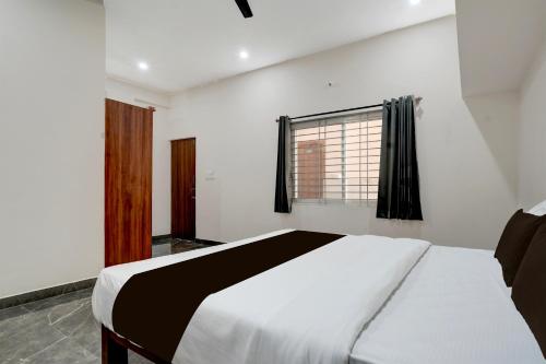 a bedroom with a white bed and a window at Hotel O Ambari Residency in Kadakola