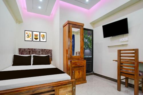 a bedroom with a bed and a tv and a chair at Hotel O Siva Jyothi in Venjāramūdu