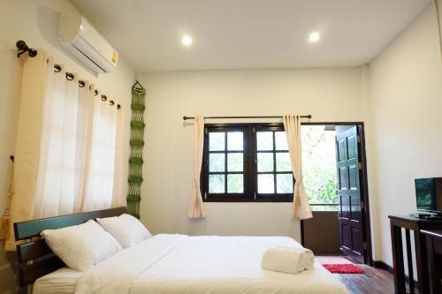 1 dormitorio con cama y ventana en Kittawan Home&Gallery en Chiang Mai