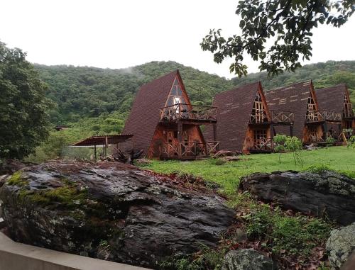 a large wooden house with a mountain in the background at Oasis Hotel & Resort Mazamitla in Caliguana