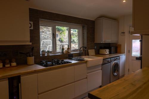 a kitchen with a stove top oven next to a window at Loom Cottage Holmfirth in Holmfirth
