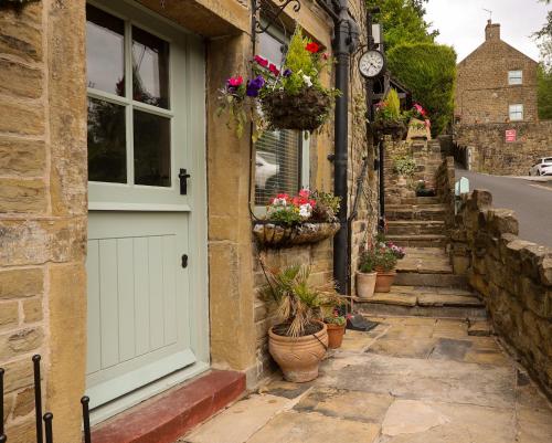 a door of a building with potted plants and a clock at Loom Cottage Holmfirth in Holmfirth