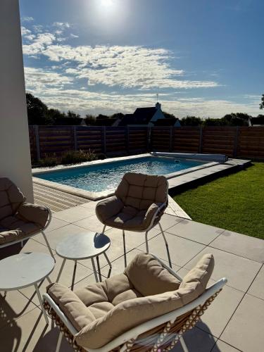 un patio avec deux chaises et une piscine dans l'établissement Port-Manech', Maison avec piscine - Plages à pied, à Kermen