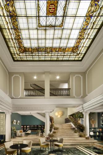 a lobby with a skylight and tables and chairs at NH Madrid Nacional in Madrid