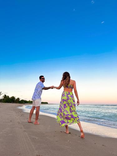 a man and woman holding hands on the beach at Milagres de Minas in São Miguel dos Milagres