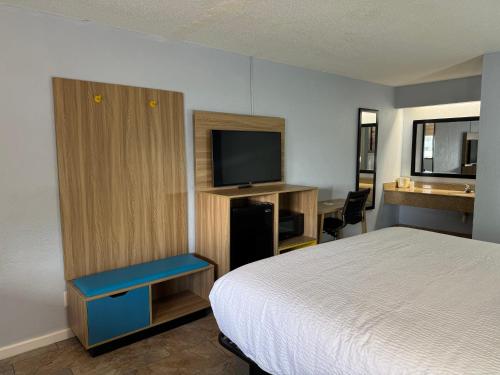 a hotel room with a bed and a television at Days Inn by Wyndham Charlotte University in Charlotte