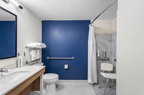 a bathroom with a toilet and a blue wall at Spark by Hilton Alpharetta Roswell in Alpharetta