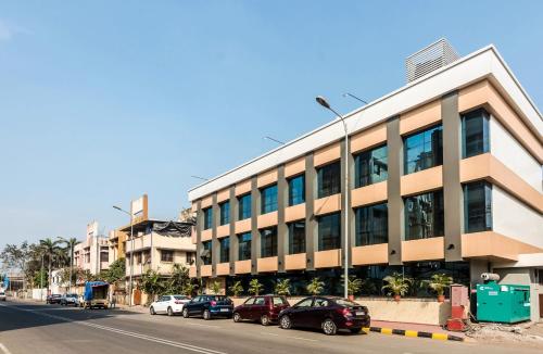 a building with cars parked in front of a street at Capital O Hotel Konar Inn in Turambhe