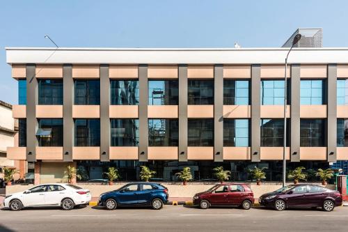 a building with cars parked in a parking lot at Capital O Hotel Konar Inn in Turambhe