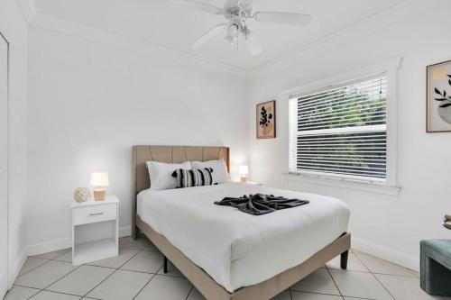 a white bedroom with a bed and a window at Miami home -15min from Kendall Exec Airport - Pool in Hammocks