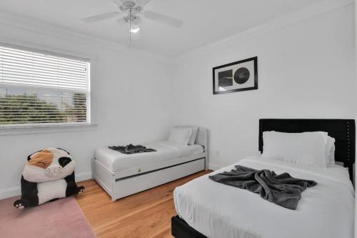 a white bedroom with two beds and a window at Miami home -15min from Kendall Exec Airport - Pool in Hammocks