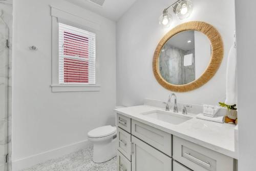 a white bathroom with a sink and a mirror at Talk To The Sand in Bailey Hall