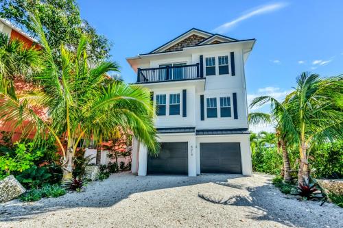 a white house with palm trees in front of it at Talk To The Sand in Bailey Hall