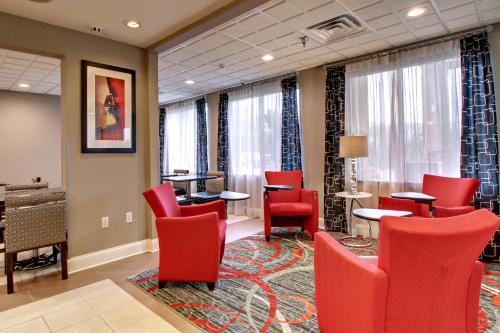 a waiting room with red chairs and tables and windows at Holiday Inn Express Hurricane Mills Waverly by IHG in Hurricane Mills