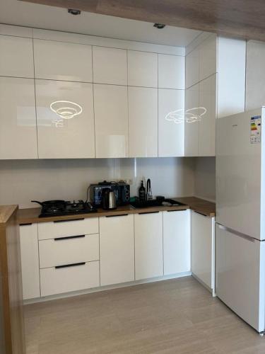 a kitchen with white cabinets and a refrigerator at Аренда квартир in Bishkek