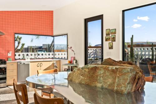a kitchen with a glass table and a large rock at Stargaze Escape By The Cohost Company in Yucca Valley