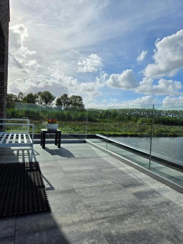 a patio with a bench and a view of the water at Villa Suite Oudshoorn in Alphen aan den Rijn