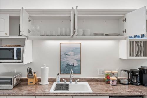 a kitchen with white cabinets and a sink at Miramar Penthouse Coastal Elegance in the Heart of Half Moon Bay in Half Moon Bay