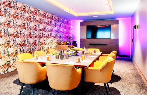 a dining room with a table and yellow chairs at NYX Hotel Mannheim by Leonardo Hotels in Mannheim