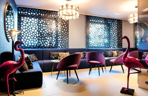 a lobby with pink chairs and a blue couch at NYX Hotel Mannheim by Leonardo Hotels in Mannheim