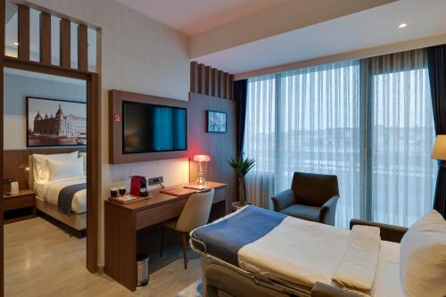 a hotel room with a bedroom with a bed and a desk at Ramada by Wyndham Istanbul Old City in Istanbul