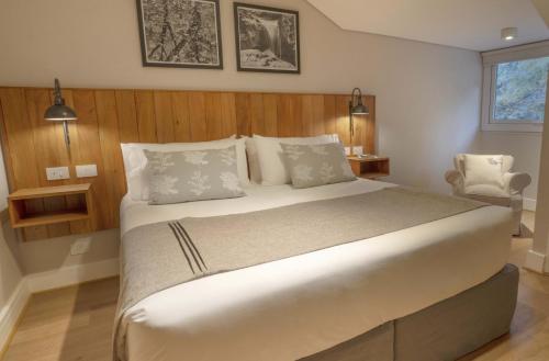 a bedroom with a large bed and a chair at La Cascada Casa Patagónica by DON in San Carlos de Bariloche
