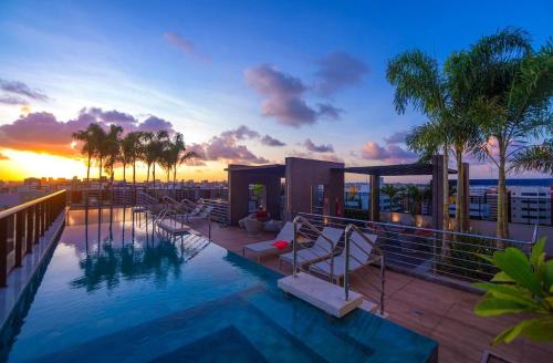 a swimming pool on top of a building with a sunset at Edifício Time Acomodações in Maceió