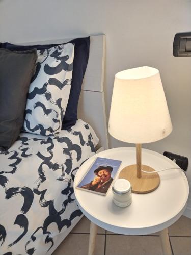 a table with a lamp and a picture on it next to a bed at un balcone sul lago in Omegna