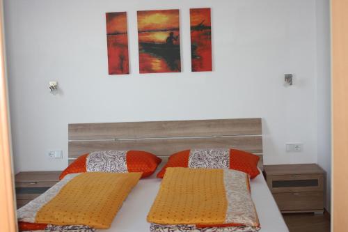 ein Bett mit zwei Kissen und einem Gemälde an der Wand in der Unterkunft Holzlehenhof in St. Johann im Pongau