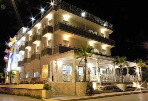 a lit up building with palm trees in front of it at GFH - Hotel Sole Resort & Spa in Marotta
