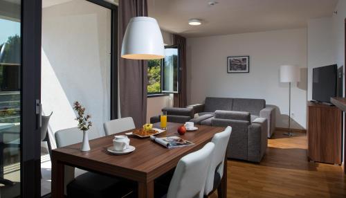 a living room with a wooden table and a dining room at Maistra Select Srebreno Premium Apartments in Mlini