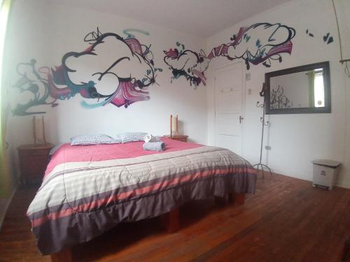 a bedroom with a bed with a painting on the wall at Hostal Po in Valparaíso