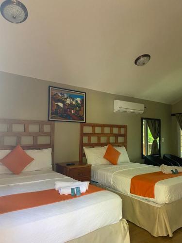 a bedroom with two beds with orange and white sheets at Villas La Montaña in Copan Ruinas