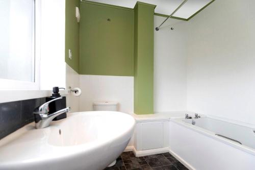 a bathroom with a white tub and a green wall at Park House in Durham