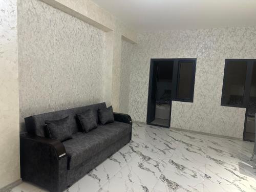 a living room with a black couch and a wall at Remember Me B&B in Dilijan