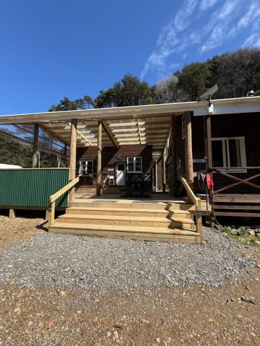 a house with a porch with a deck at White Star Station Farm Holiday Park in Coromandel Town