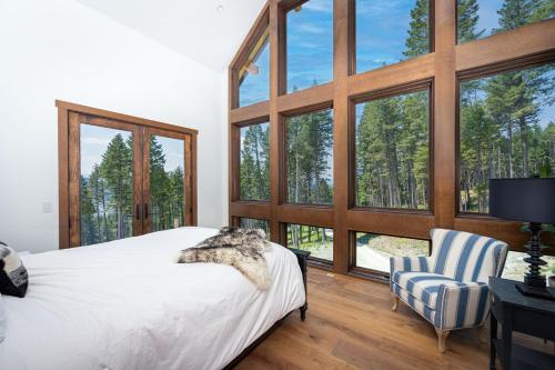 a bedroom with a bed and a chair and windows at Great Northern Mountain Escape in Whitefish