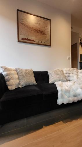 a black couch with pillows on it in a living room at Chalet Otsoak Chalet privé 3 chambres 6 personnes avec grande terrasse, garage couvert, vue montagnes à St Lary village in Saint-Lary-Soulan
