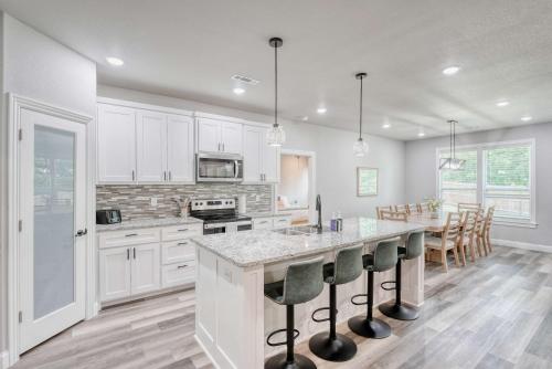 a kitchen with white cabinets and a large island with bar stools at Bike-Friendly Retreat with Fenced Yard & Trails in Dug Hill