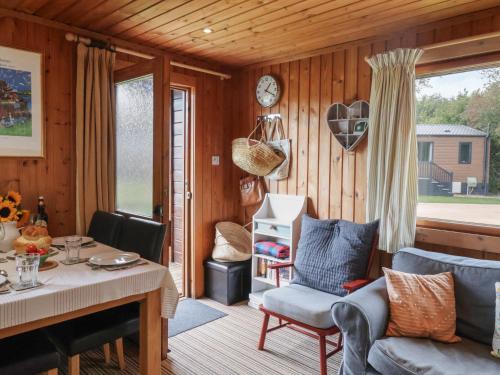 a living room with a table and chairs and a clock at 10 Pinewood Retreat in Lyme Regis
