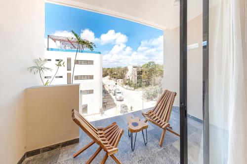 a balcony with two chairs and a view of a city at Moonlight 309 at Aldea Zama in Tulum